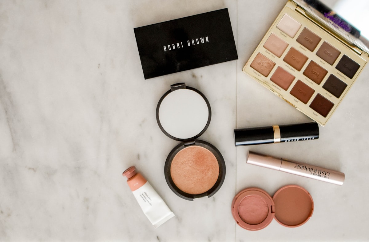Beauty product flat-lay with palette and compacts on a marble surface